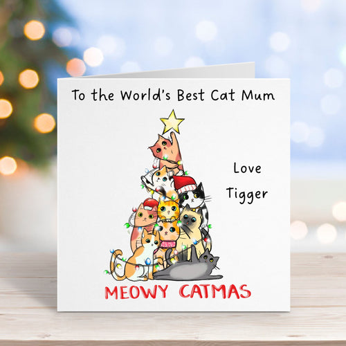 Greeting card with cartoon cats and festive text on a blurred Christmas background