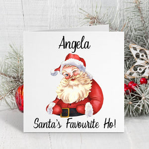Christmas card with Santa Claus illustration and text 'Angela, Santa's Favourite Ho!' on a white background with decorative elements.