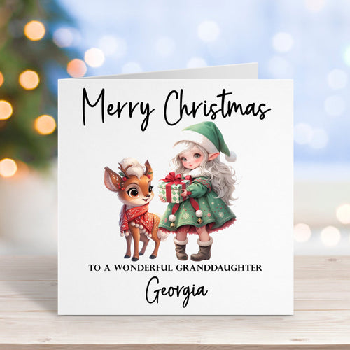 Christmas card with a deer and elf illustration on a wooden surface with blurred lights in the background