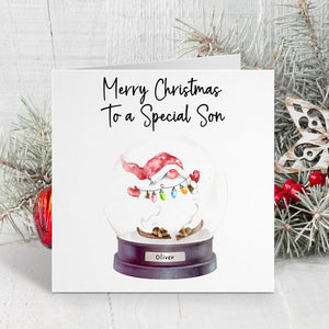 Christmas card with a snow globe featuring a Santa Claus figure and text 'Merry Christmas to a Special Son'.