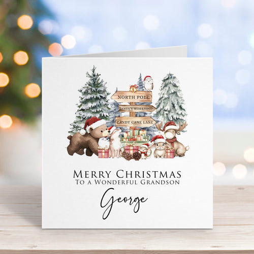 Christmas card with Santa, reindeer, and trees on a wooden surface with blurred lights in the background