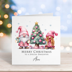 Christmas card with gnomes and tree on a wooden surface with blurred lights in the background