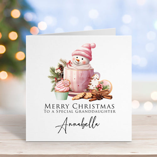 Christmas card with a snowman, mug, and cookies on a blurred Christmas tree background