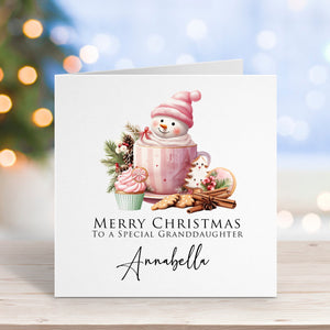 Christmas card with a snowman, mug, and cookies on a blurred Christmas tree background