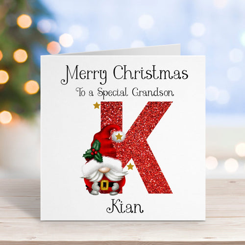 Christmas card for a special grandson with a red 'K' and gnome illustration, on a blurred festive background.