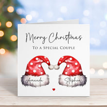 Christmas card with two Santa hats and personalized names on a blurred festive background