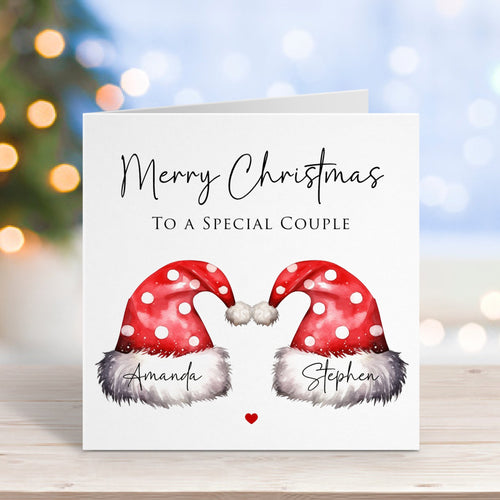 Christmas card with two Santa hats and personalized names on a blurred festive background